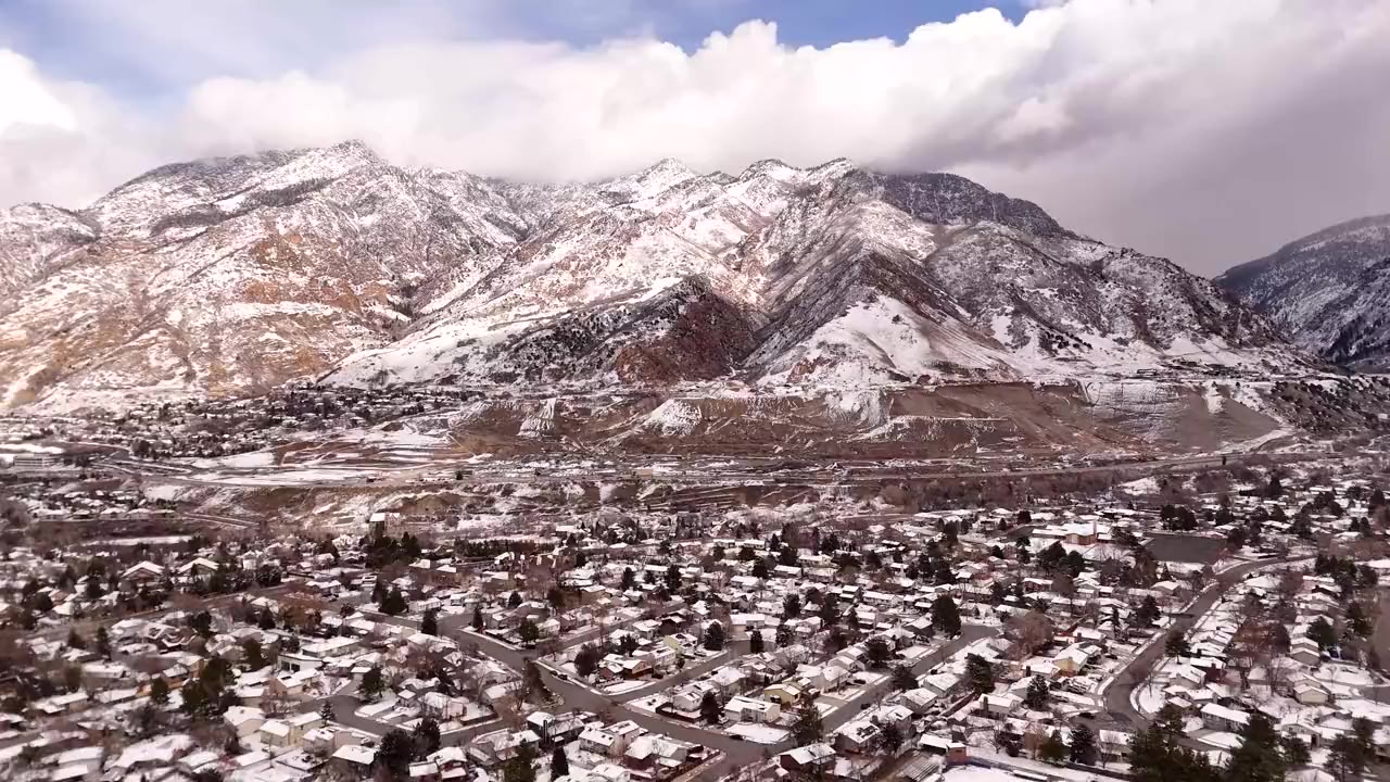 Aerial view of a Wasatch Front neighborhood below snow-covered mountains